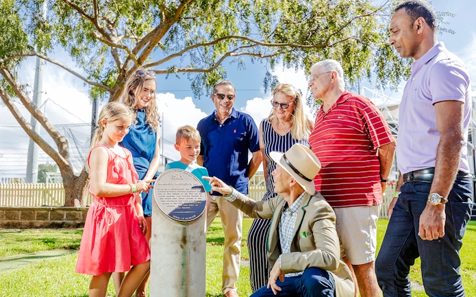 Tour group with guide at Sydney Cricket Ground, viewing a commemorative plaque.