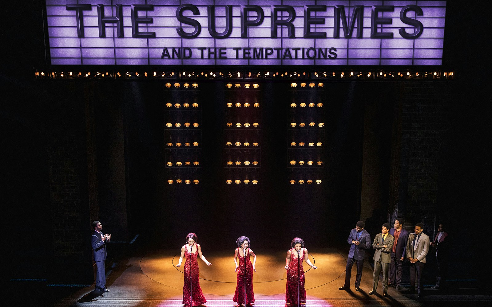 Performers on stage under "The Supremes and The Temptations" sign in Ain't Too Proud musical.
