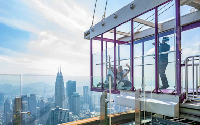 Tourists in Kuala Lumpur Tower Glass Box with city skyline view.