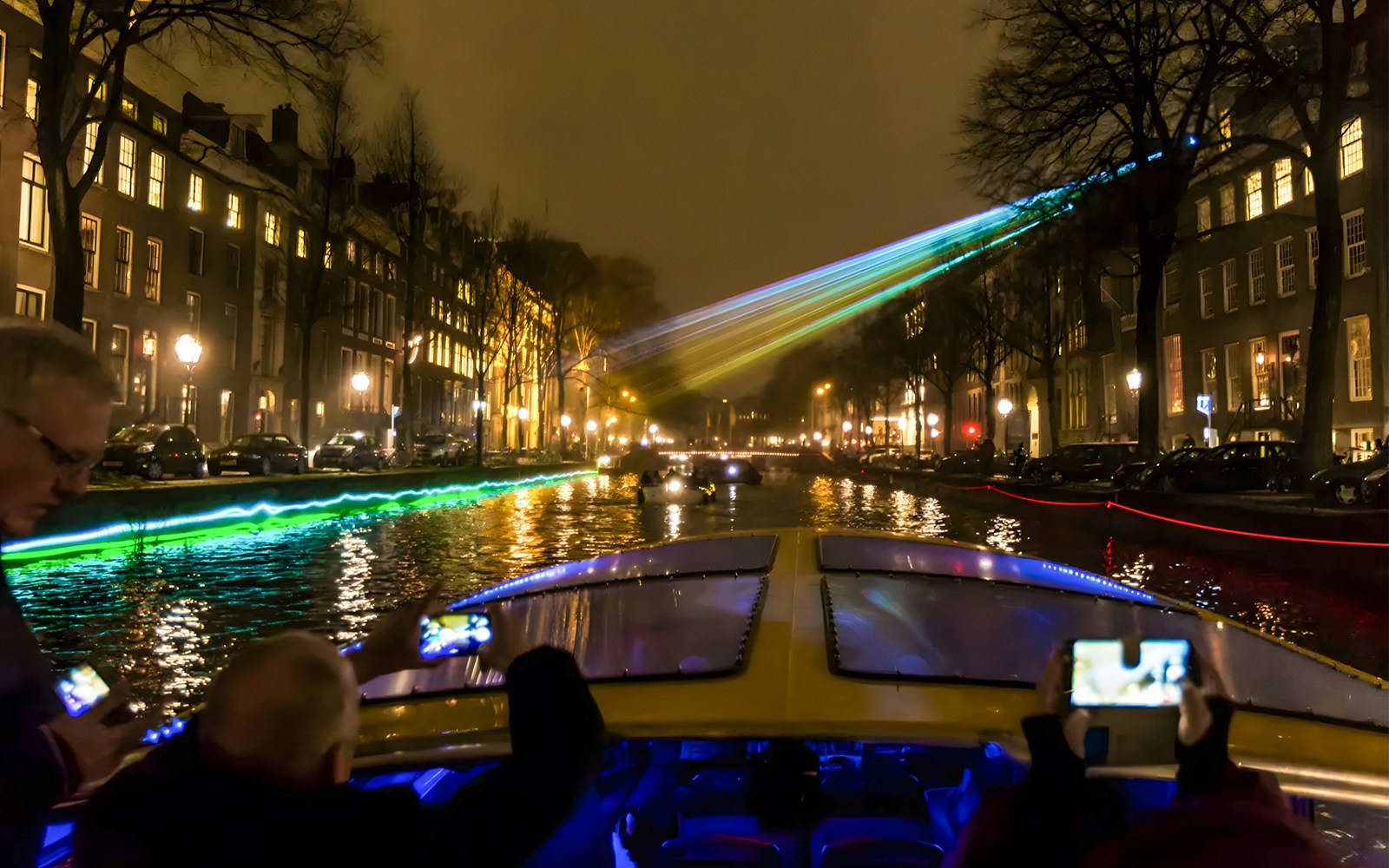 Amsterdam Light Festival cruise boat on illuminated canal at night.
