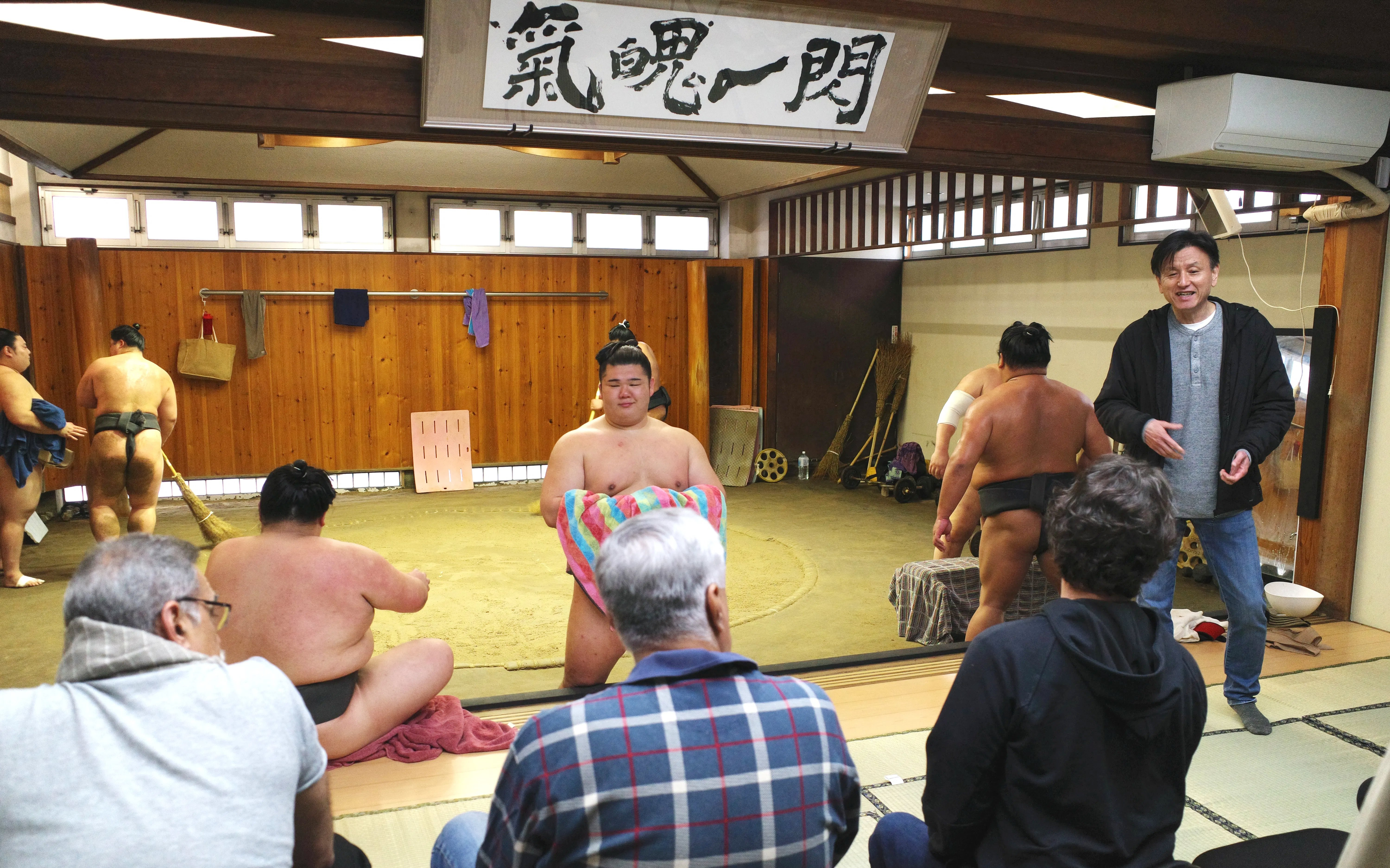 Sumo wrestlers practicing in a traditional Asakusa dojo with spectators watching.