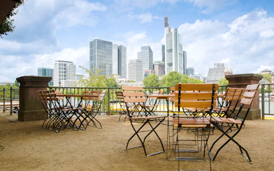Cafe tables and chairs overlooking Frankfurt cityscape with skyscrapers.