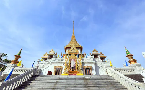 Wat Traimit temple in Bangkok with ornate golden spire and staircase.
