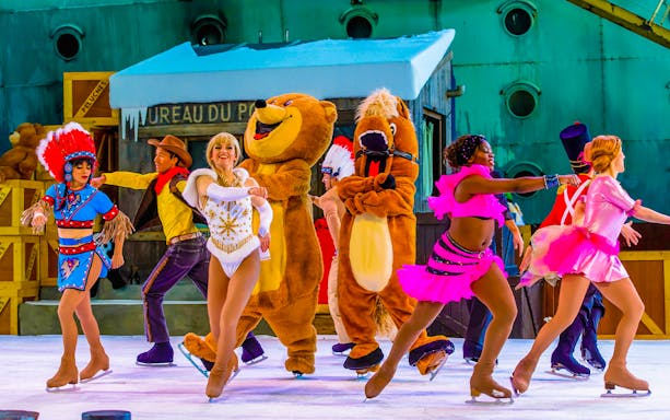 Performers in colorful costumes ice skating at Astérix Park show.