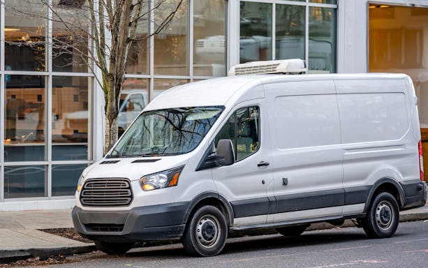 Tour van for Cape Sounion sunset excursion parked on city street.