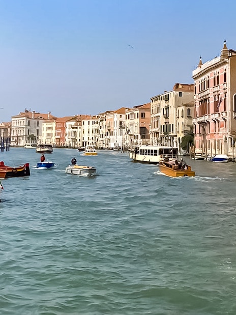 Sightseeing boats on Venice's Grand Canal with historic buildings lining the waterway.