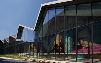 Glass facade of Krakow museum reflecting portraits, part of the Krakow Museum Pass tour.