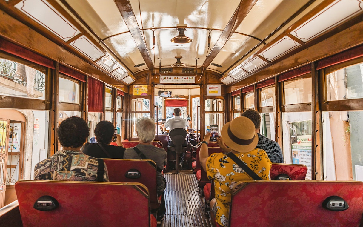 Tourists photographing views from inside a Lisbon tramcar.