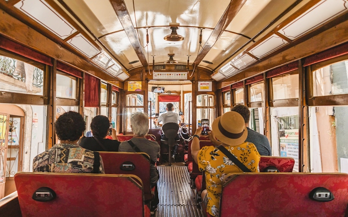 Tourists photographing views from inside a Lisbon tramcar.