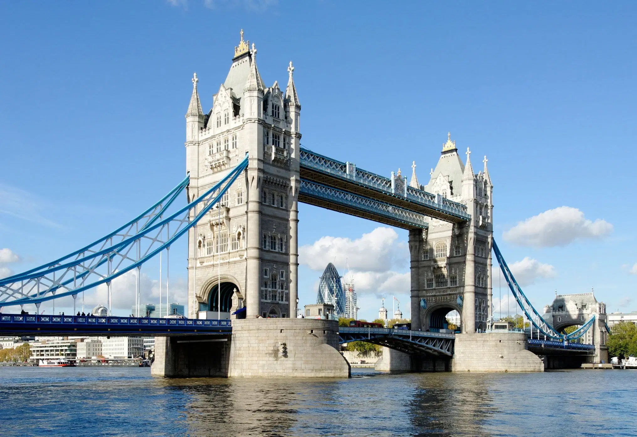Tower Bridge spanning the River Thames in London, with the Gherkin in the background.