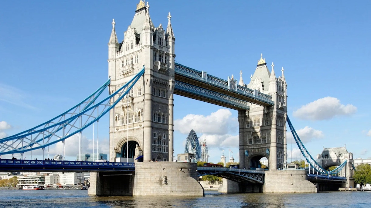 Tower Bridge spanning the River Thames in London, with the Gherkin in the background.