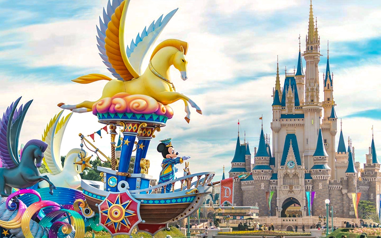 Mickey Mouse on a colorful float at Tokyo DisneySea with a castle in the background.