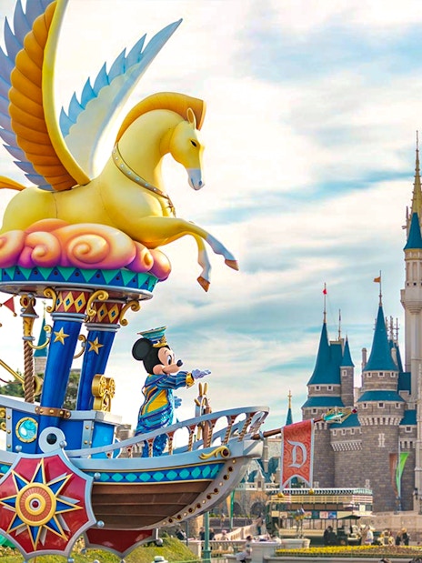 Mickey Mouse on a colorful float at Tokyo DisneySea with a castle in the background.