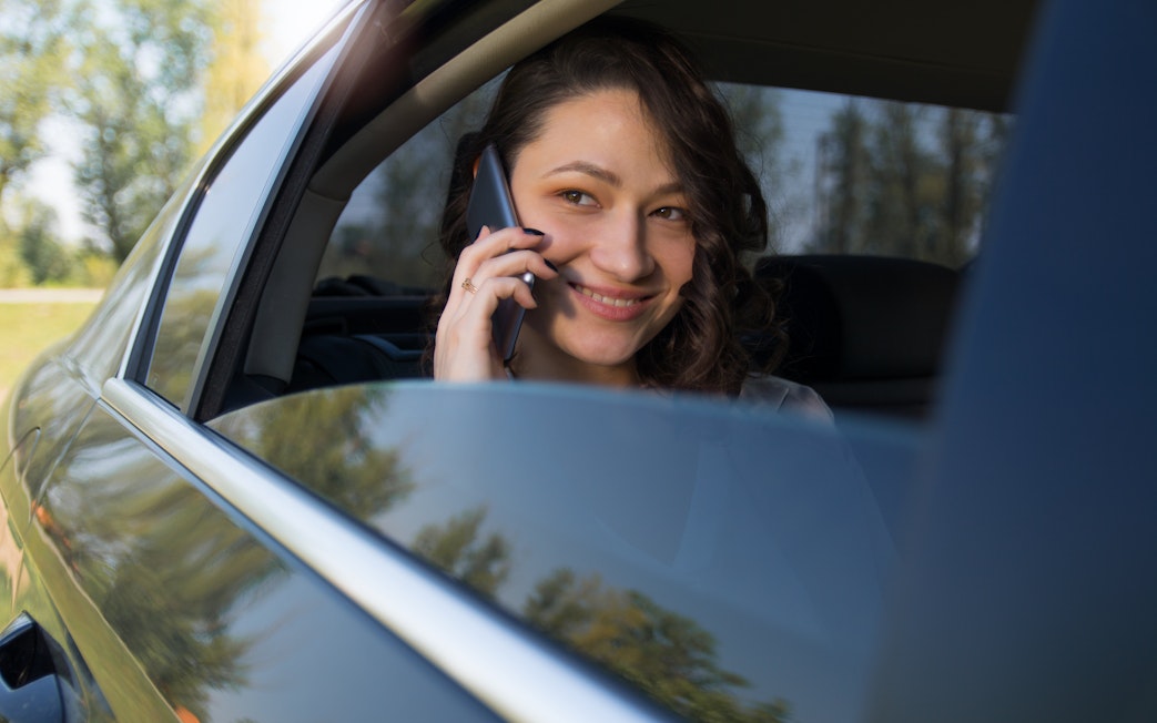 Woman talking on phone in backseat of car.