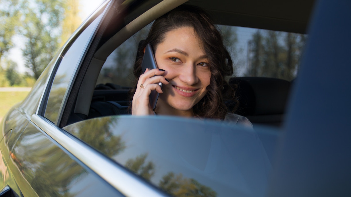 Woman talking on phone in backseat of car.