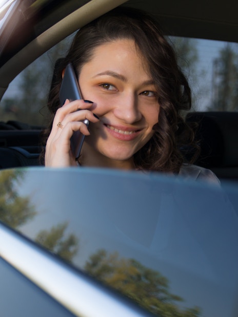 Woman talking on phone in backseat of car.