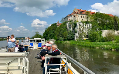 Vistula River cruise with tourists viewing Tyniec Abbey near Krakow.