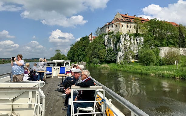 Vistula River cruise with tourists viewing Tyniec Abbey near Krakow.