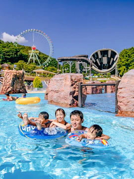 Family enjoying water park attractions at Tokyo Summerland with Ferris wheel in background.