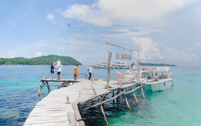 Speed boat docked at May Rut Beach Bar, Phu Quoc, with tourists on a wooden pier.