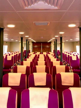 Interior seating of Sindo Ferry with rows of red seats and white headrests.
