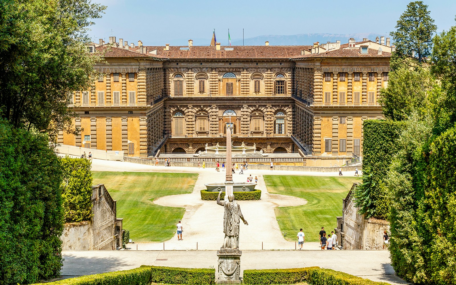 Gardens and exterior view of Pitti Palace in Florence, Italy, with visitors exploring.