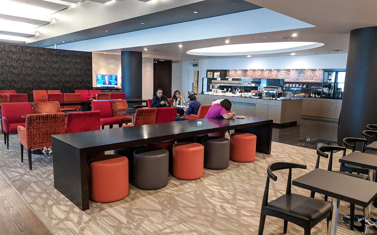 Plaza Premium Lounge seating area with guests and buffet in the background.