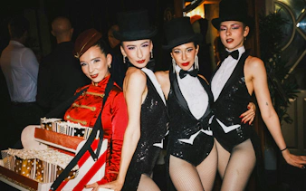 Performers in sequined outfits and top hats at a Burlesque Dinner Club in Vienna.
