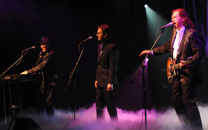 Performers on stage during The Australian Bee Gees Show with instruments and microphones.