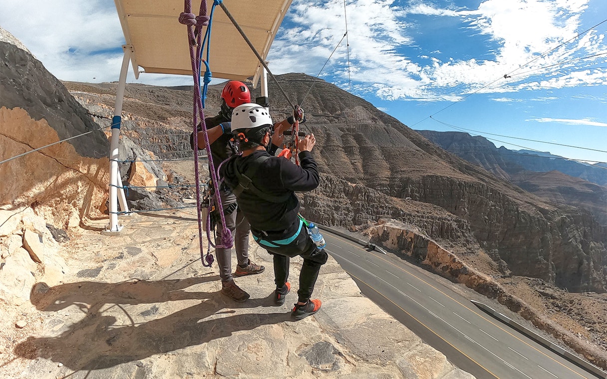 Tourist preparing to zipline at Jebel Jais, Dubai with mountainous landscape in view.