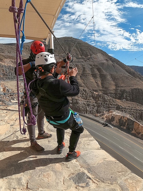 Tourist preparing to zipline at Jebel Jais, Dubai with mountainous landscape in view.