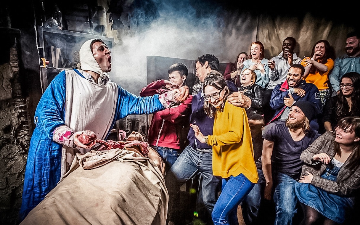 Visitors react to a theatrical performance at The London Dungeon.