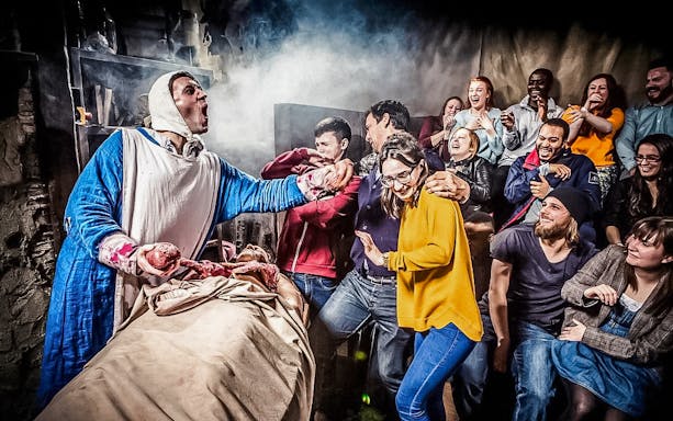 Visitors react to a theatrical performance at The London Dungeon.