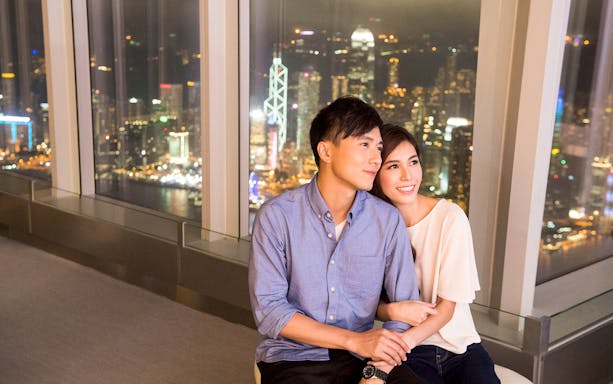 Couple enjoying night view of Hong Kong skyline from Sky100 observation deck.