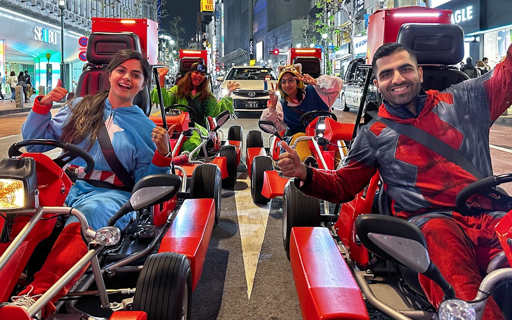 Participants in costumes on go-karts during a street tour in Shibuya, Tokyo.