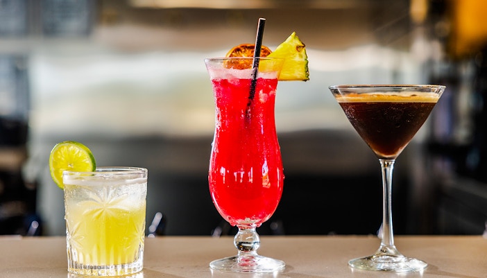 Cocktails on bar featuring lime, pineapple, and espresso drinks.
