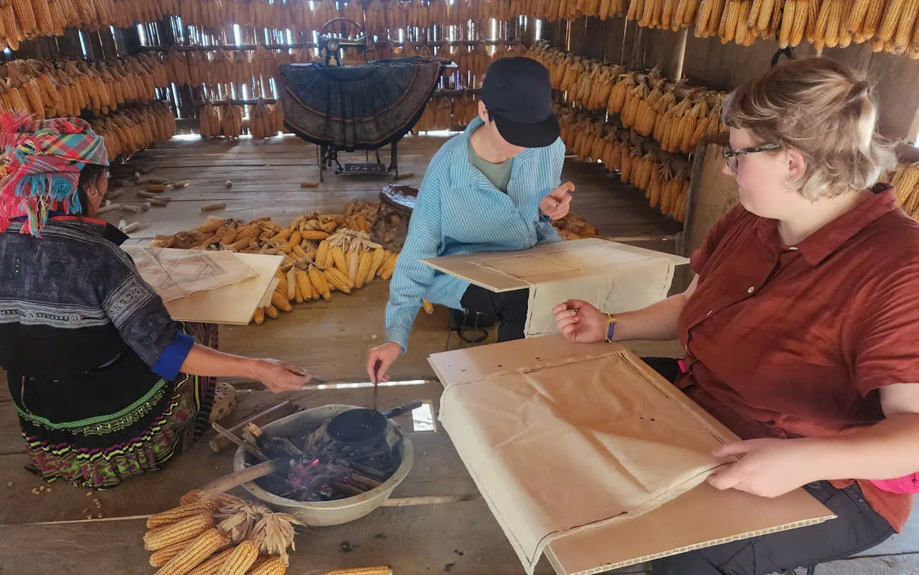 Local guide and tourists crafting in a corn storage house during Mu Cang Chai private car tour.