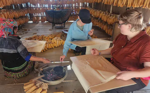 Local guide and tourists crafting in a corn storage house during Mu Cang Chai private car tour.