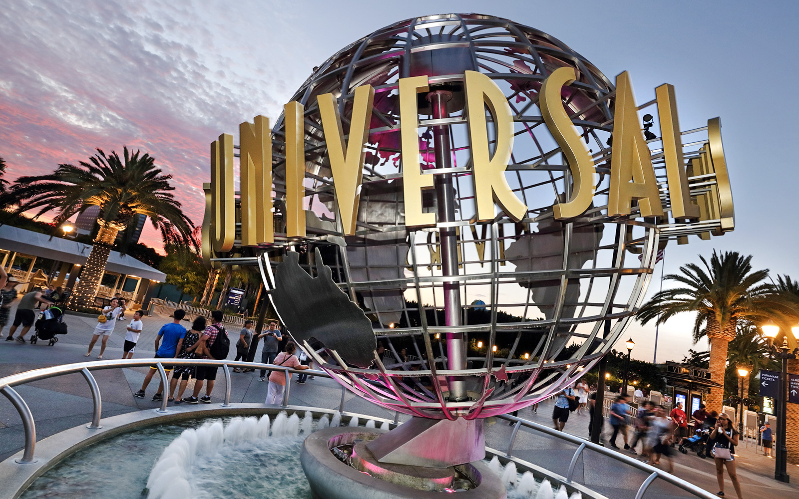 Universal Studios Hollywood entrance globe with visitors nearby.