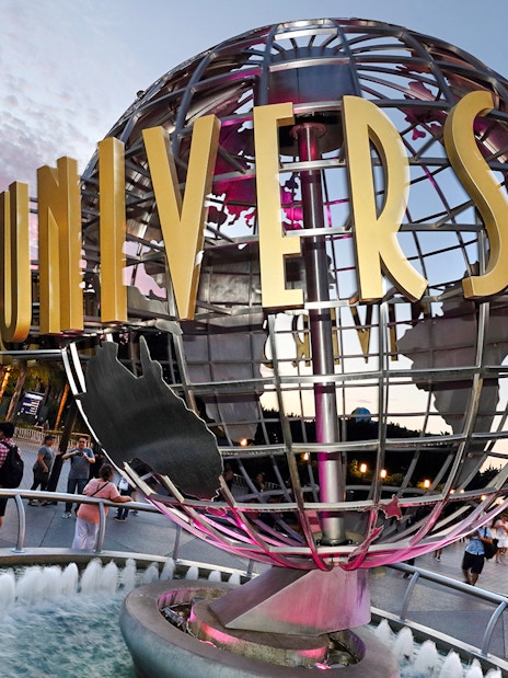Universal Studios Hollywood entrance globe with visitors nearby.