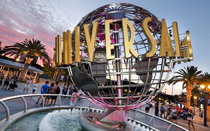 Universal Studios Hollywood entrance globe with visitors nearby.