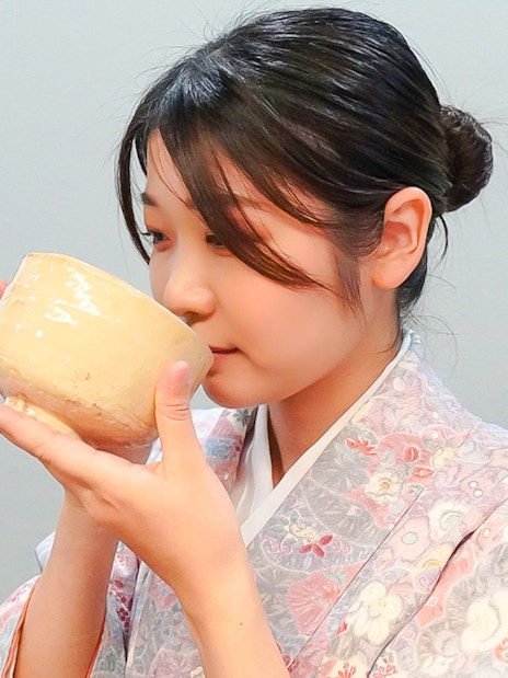Woman in kimono sipping matcha from a traditional bowl in Japan.