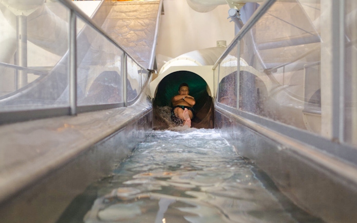 Person sliding down Saturn slide in Galaxy Zone at Therme Bucharest.