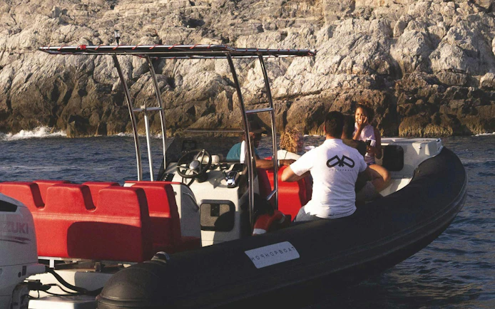 Boat with tourists near rocky coastline on La Spezia: Portovenere and 3 Islands trip.