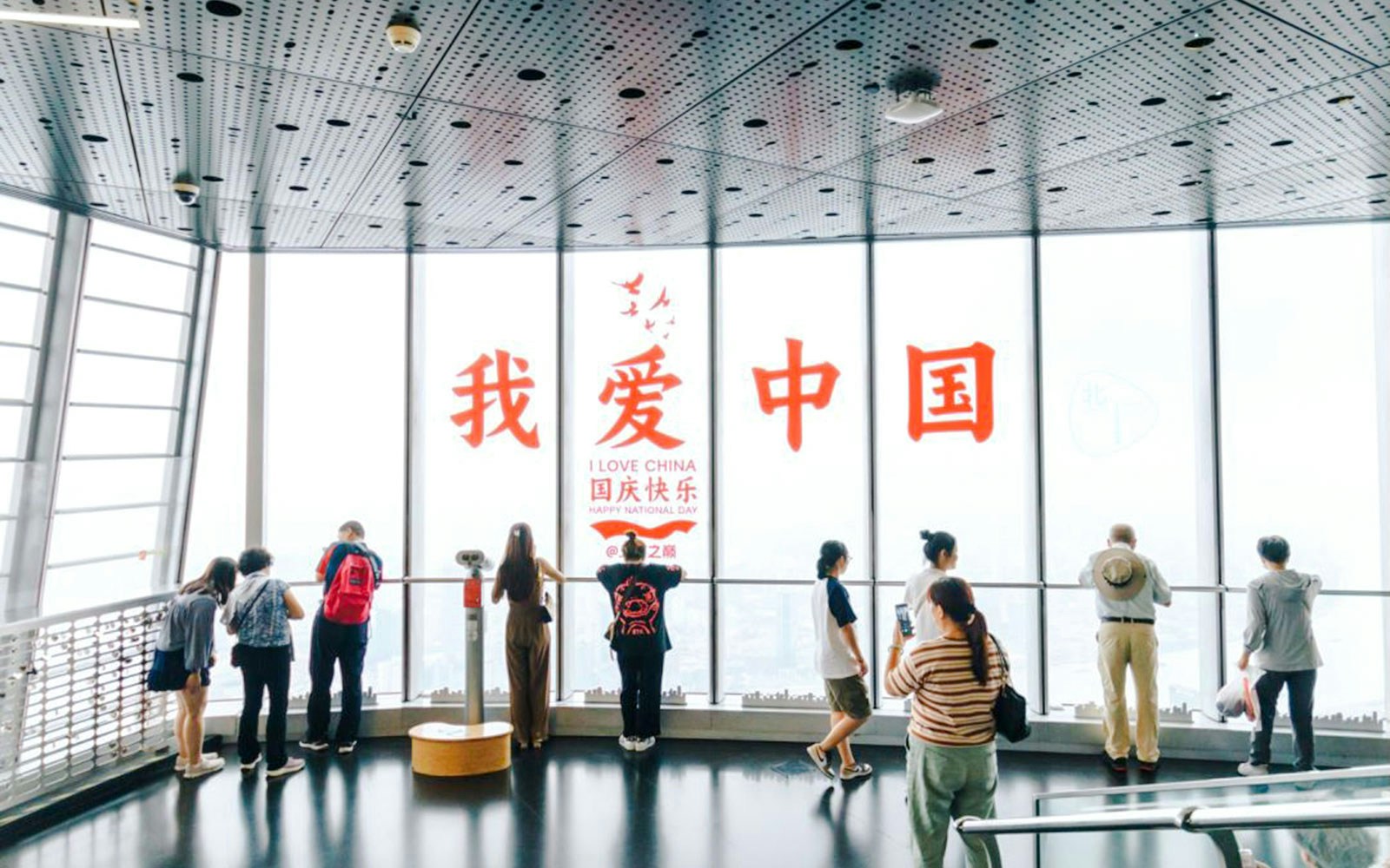 Visitors at Shanghai Tower observation deck with "I Love China" sign.
