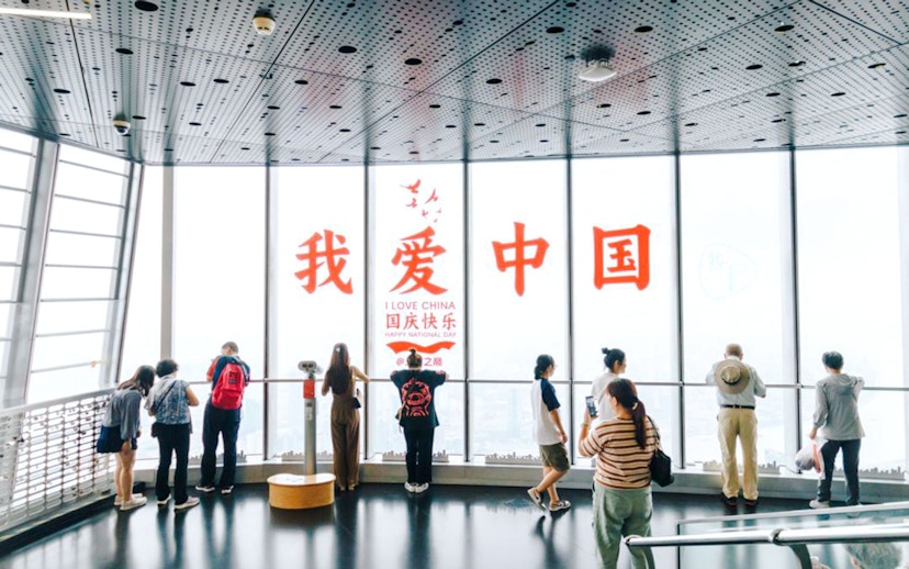 Visitors at Shanghai Tower observation deck with "I Love China" sign.