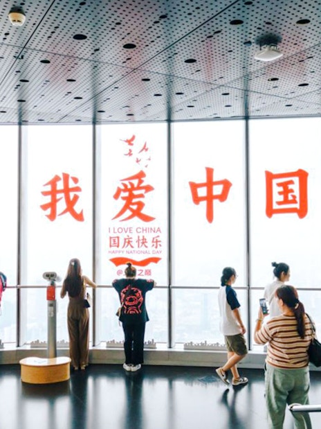 Visitors at Shanghai Tower observation deck with "I Love China" sign.