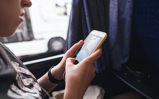 Passenger using smartphone with WiFi on bus from London Stansted Airport to Stratford.