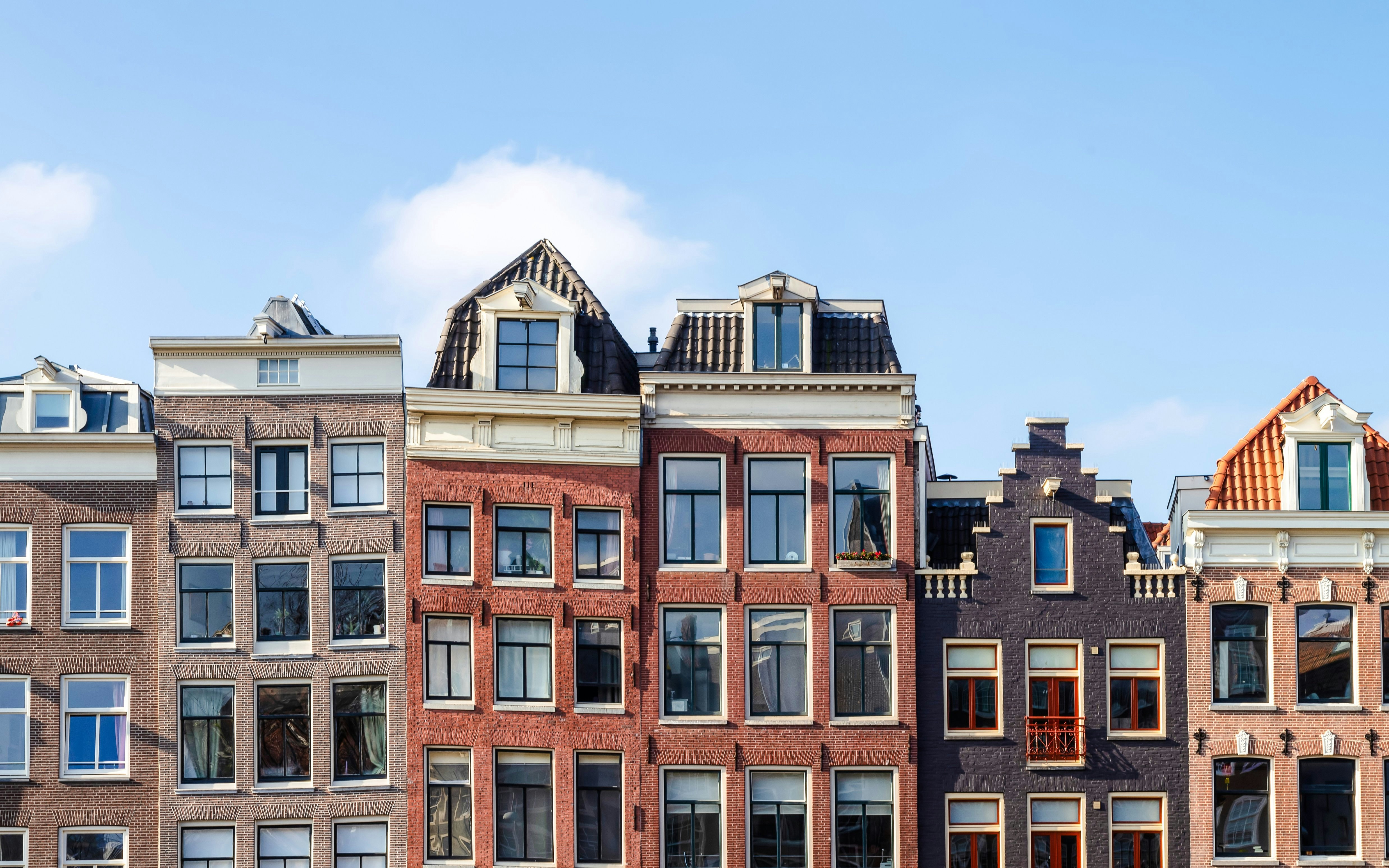 Amsterdam canal houses with gabled roofs and large windows.