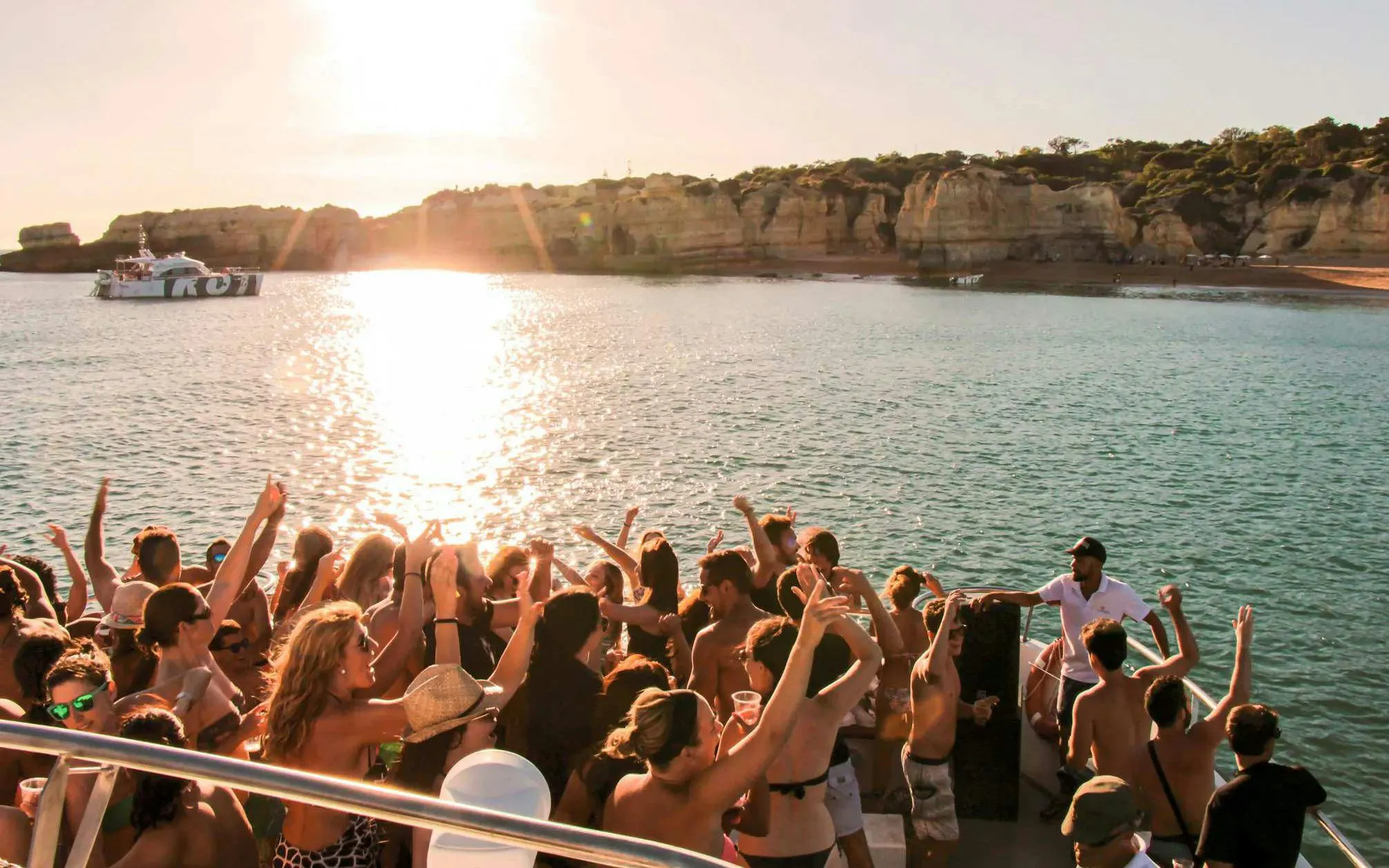 Partygoers enjoying a sunset cruise with DJ on Albufeira's Algarve coast.